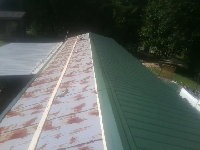 Old rusted panels beside newly installed green metal roofing — Wind Damage Roof Repair by Roofing Brothers in Rigby