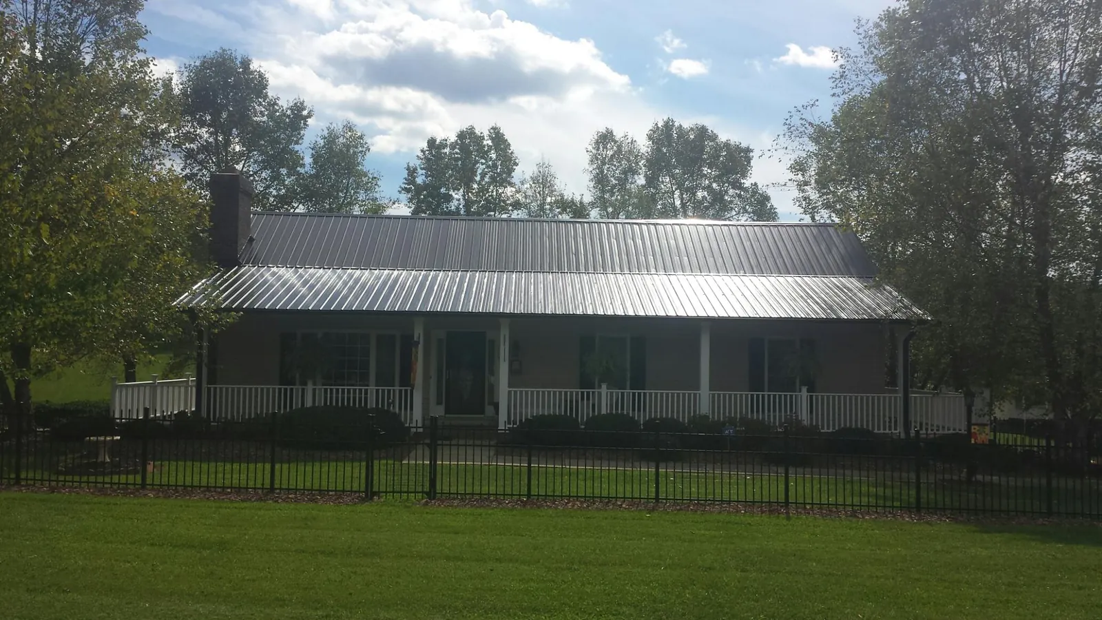 Gray metal roof on a brick ranch with a full width front porch — Gutter Guard Installation work by our crew in Rigby