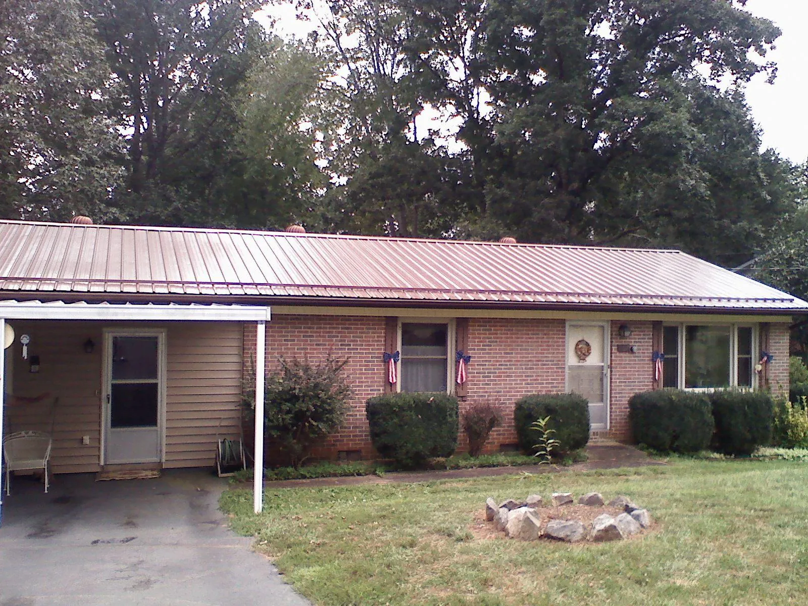 Bronze metal roof and carport on a brick ranch home — Roof Repair work by our crew in Rigby